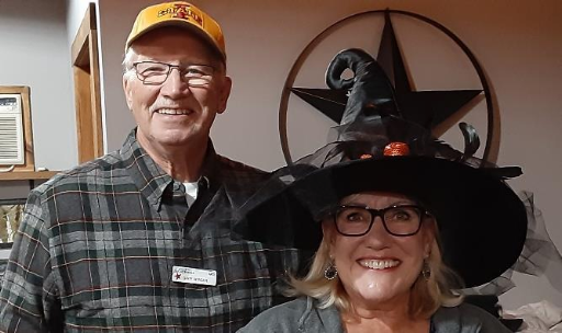 Woman wearing a witches hat next to a man in a baseball cap.